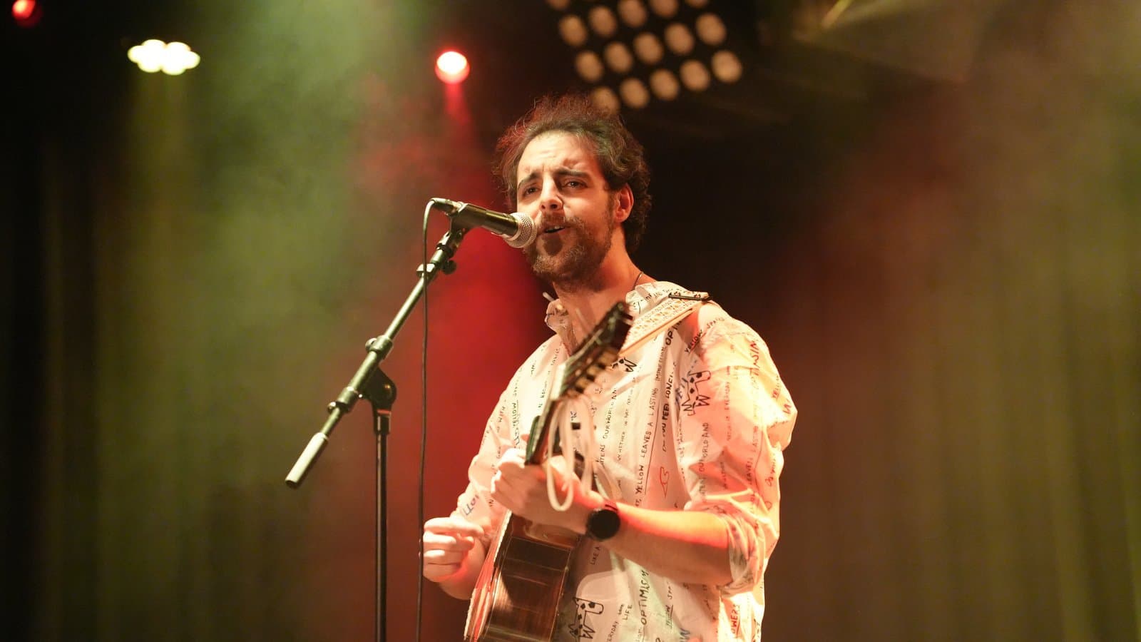 Guitarist singing passionately under warm stage lights